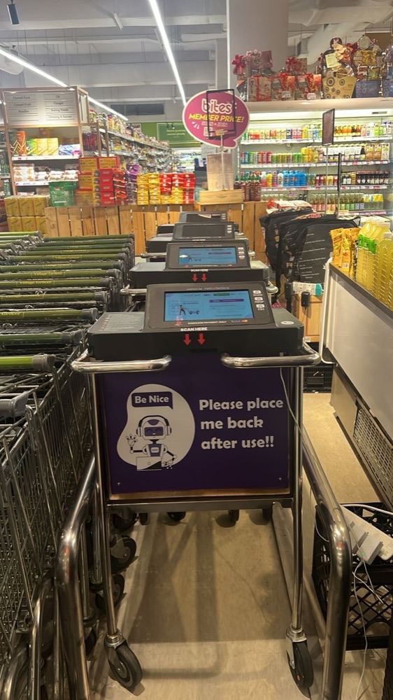 Smart trolley deployed in a supermarket aisle, screen showing myCart by retailetics, scan here instructions